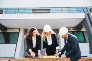 3 people wearing helmets looking construction project plan